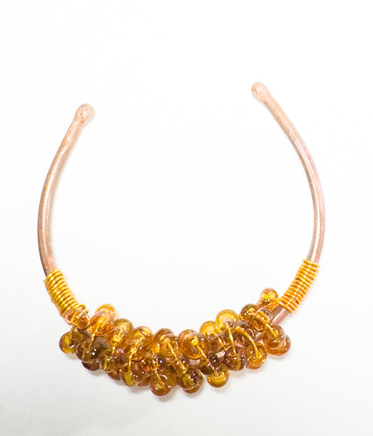 This copper-banded bracelet displays amber beads creating a sophisticated look for any ensemble.