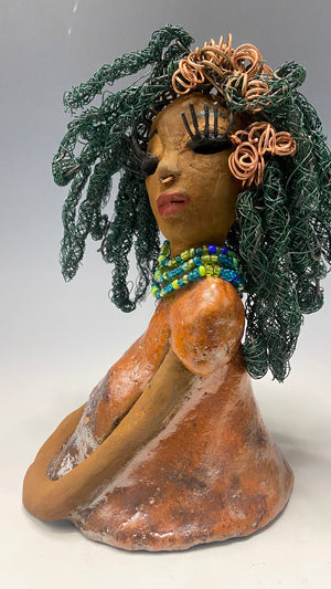 Carmine measures 9" x 6" x 5.5" and weighs 2 lbs, with honey brown complexion and reddish brown lips. Her long hair boasts copper strands and over 80 feet of 24 and 16 gauge twisted wire, reaching her waist. She has vibrant metallic copper red antique glazed eyes that impart a feeling of hope, and her charming presence will always initiate conversations