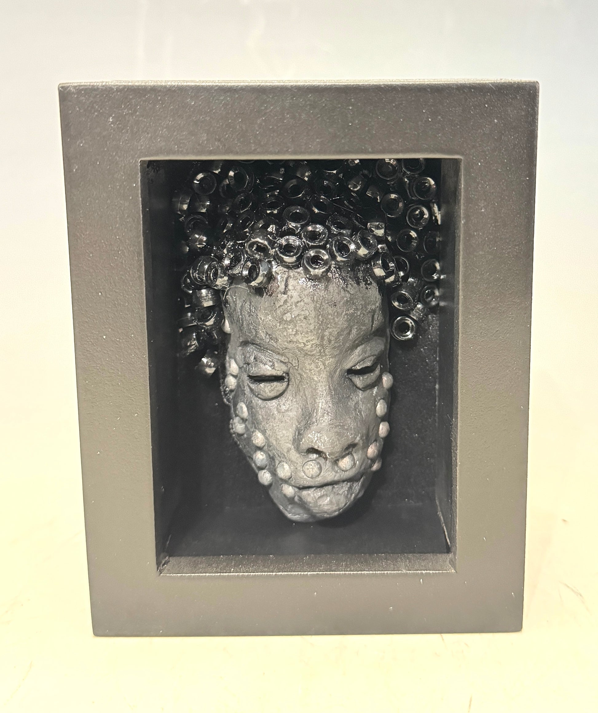Randy is a mask that is raku fired and is enclosed in a 4“ x 4“ black shadowbox. He has over 50 pony beads as hair. He has over 50 pony beads as hair!