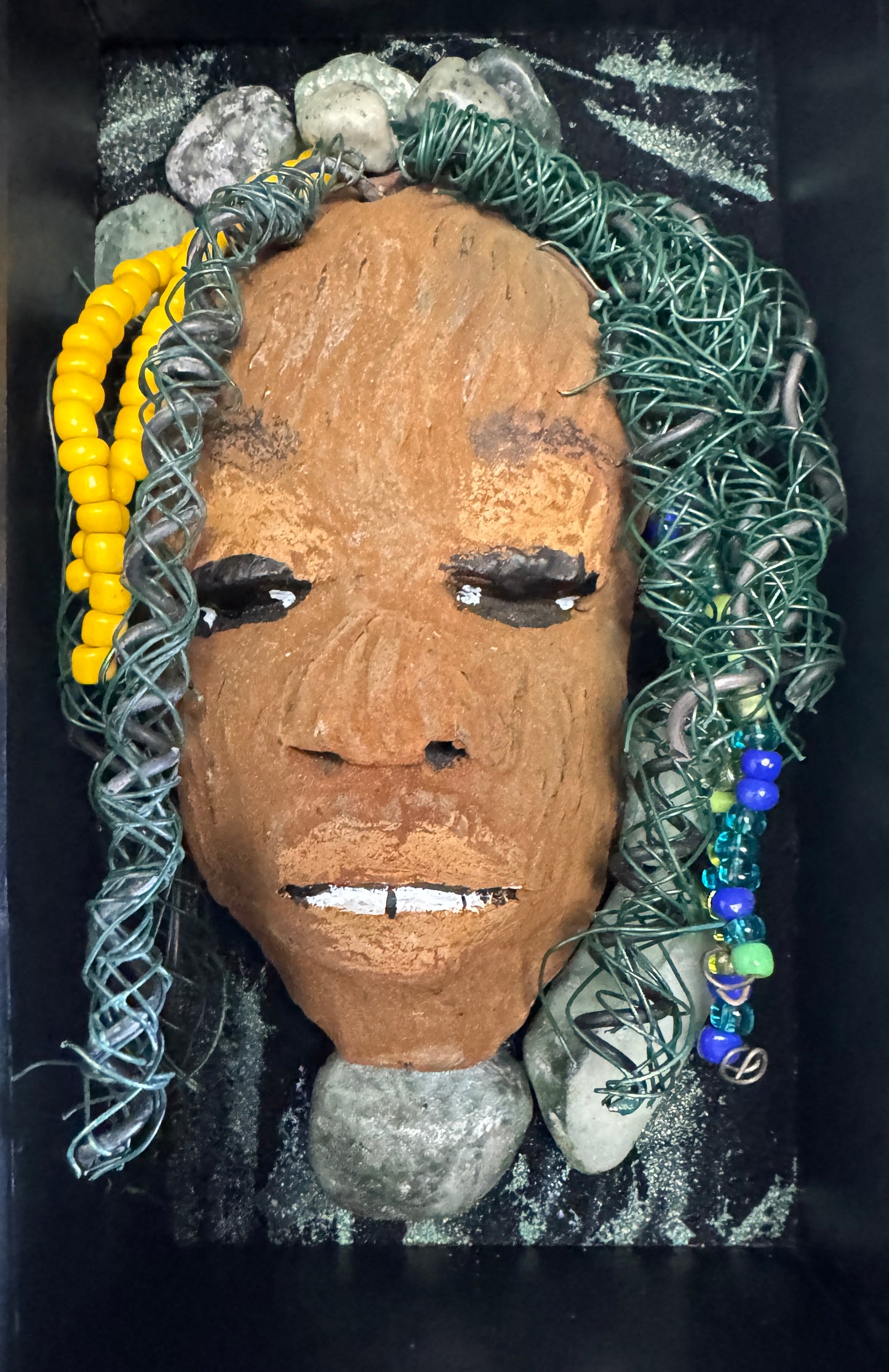 Jessie is a "4 x 6" raku mask displayed in a glass covered black shadowbox, accented with a beautiful two-tone honey brown complexion. Her intricate hair, made of 16 and 24 gauge wire, measures over 50 feet in length. With a contagious smile, Jessie adds a touch of elegance to any home decor.