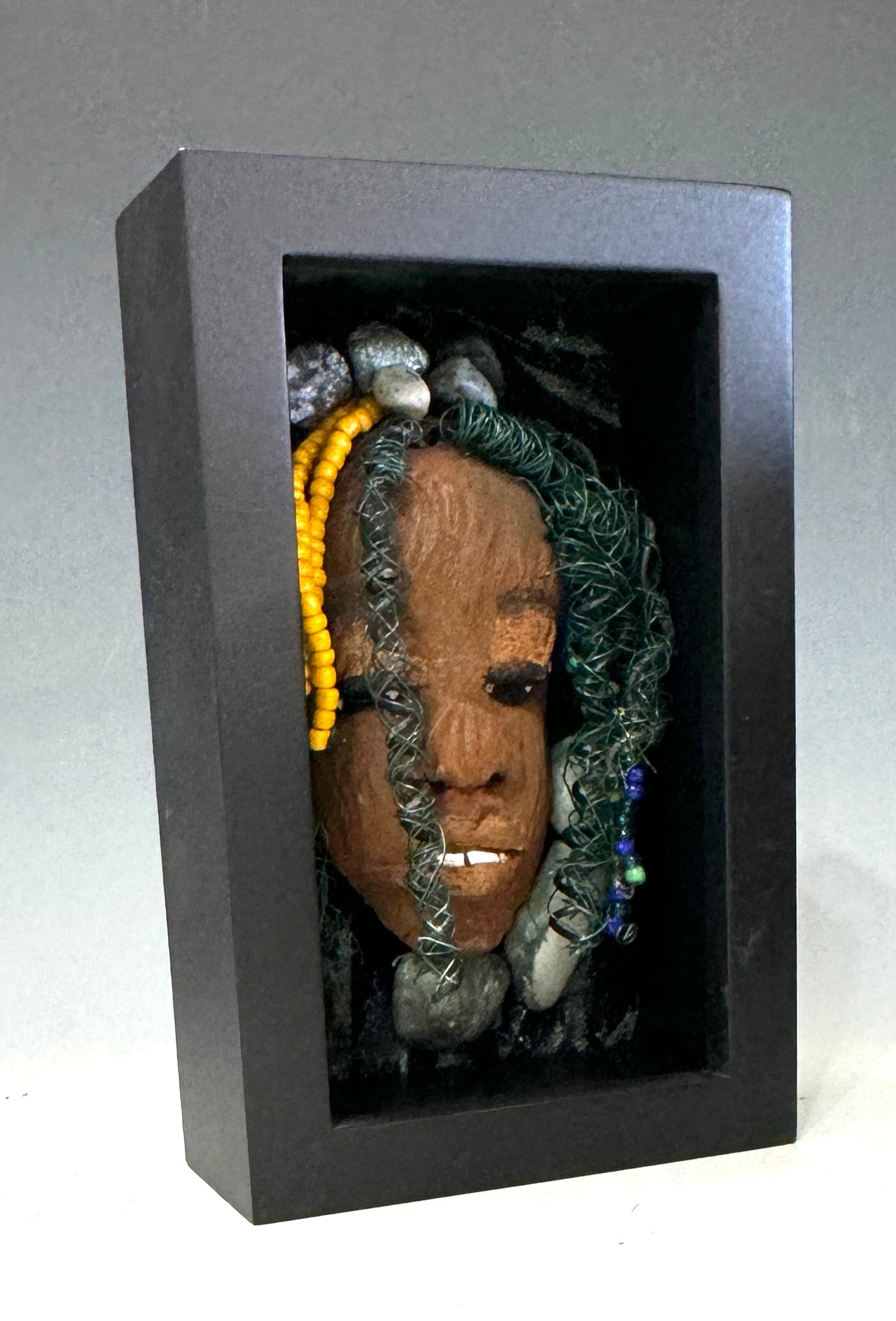 Jessie is a "4 x 6" raku mask displayed in a glass covered black shadowbox, accented with a beautiful two-tone honey brown complexion. Her intricate hair, made of 16 and 24 gauge wire, measures over 50 feet in length. With a contagious smile, Jessie adds a touch of elegance to any home decor.