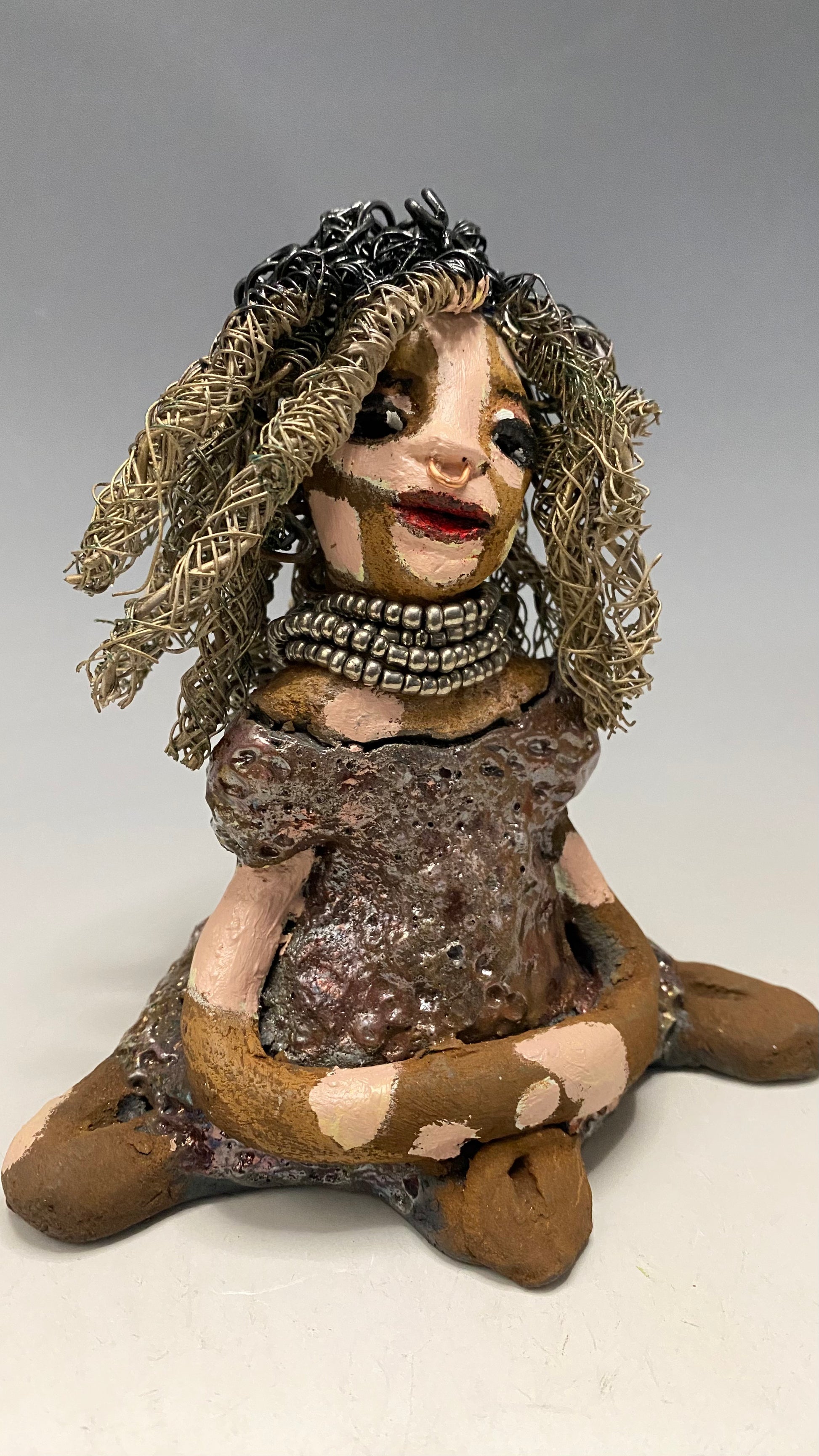 Anita stands 6.5" x 6" x 3" and weighs 1.3 lbs., with vitiligo. She loves the skin she's in! Her lips are painted with a warm ruby red, and long twisted white and gold wire locs that extend to her waist give her a unique style. Her dress is finished with a copper-antique glaze and over 75 feet of 16 and 24 gauge wire. Her bright eyes evoke a sense of hope. Add Anita to your family and she'll sure to be a conversation starter. Have questions? Ask away!