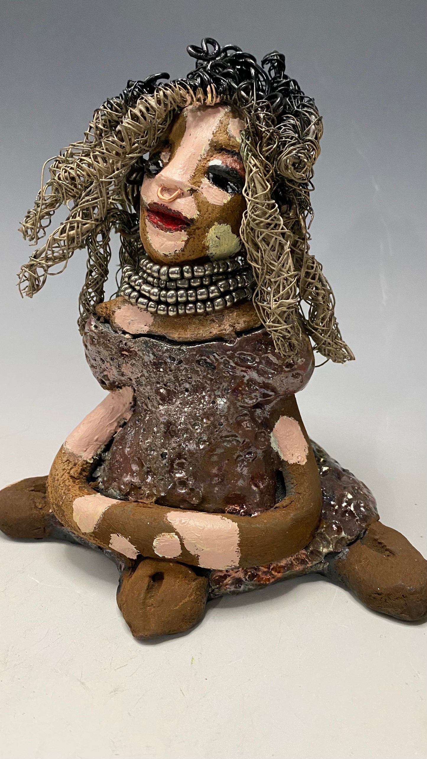 Anita stands 6.5" x 6" x 3" and weighs 1.3 lbs., with vitiligo. She loves the skin she's in! Her lips are painted with a warm ruby red, and long twisted white and gold wire locs that extend to her waist give her a unique style. Her dress is finished with a copper-antique glaze and over 75 feet of 16 and 24 gauge wire. Her bright eyes evoke a sense of hope. Add Anita to your family and she'll sure to be a conversation starter. Have questions? Ask away!