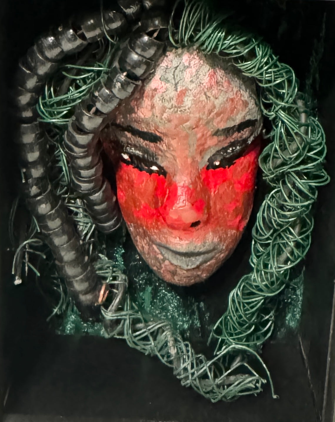 Adia is a striking mixed media mask, raku fired and displayed in a sleek black shadowbox. With over 25 feet of wire for his hair, this unique piece adds an adventurous touch to any space and showcases your bold style. Don't settle for ordinary - stand out with Adia.