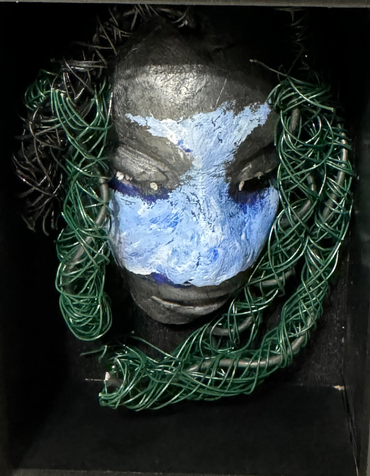 Chandon is a raku fired mask .He is enclosed in a 4“ x 4“ glass covered black shadowbox. He has over 40 feet of 16 and 24 gauge wire as hair. Make a bold statement with this striking mask! Enclosed in a sleek glass shadowbox, Chandon features a unique raku firing technique that makes each creation one-of-a-kind. The wire "hair" extends over 40 feet in length, representing a spirit that is free to explore and take risks. Bring a touch of adventure into your home with this handcrafted piece.