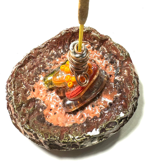 This 1" x 3" x 3" incense holder has been expertly crafted with orange transparent glass with orange beads and coated in a copper high gloss Raku glaze. It's the perfect mix of classic and cool - an artistic piece of eye-catching flair for any room!