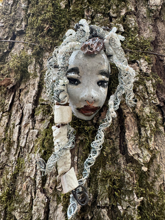 Faye is an absolutely stunning 4" x 4", 4.2 oz. Raku-fired mask with a white complexion, intricate beaded hair, and a one-of-a-kind portrait setting of a majestic tree. She's sure to make a statement indoors or outdoors - an artful gift for nature admirers and décor fans alike!