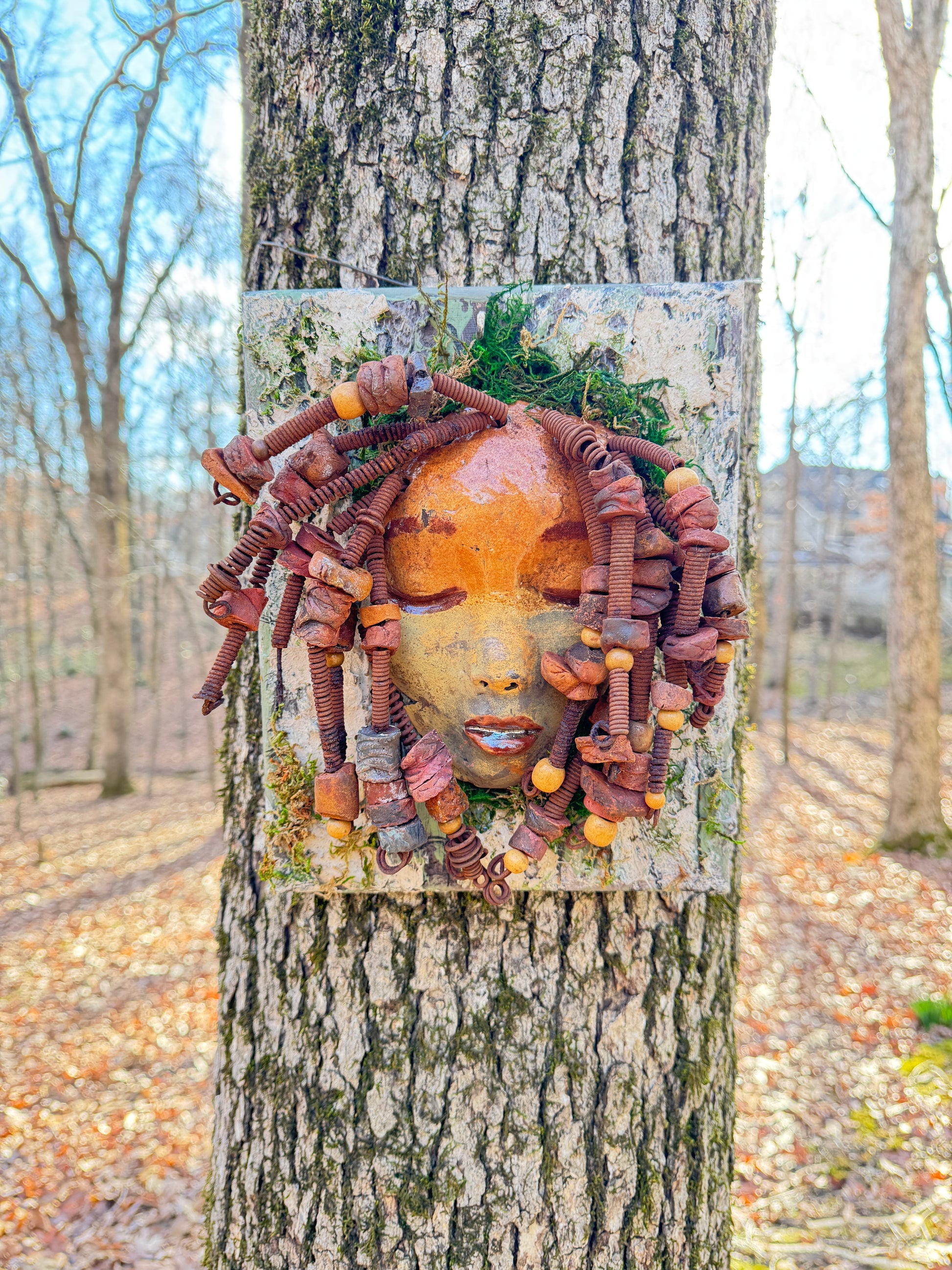 Discover the stunning aesthetic of EL Lay, a handmade raku fire mask adorned with 50 beads and crafted using 24 and 16 gauge wire. This one-of-a-kind piece weighs roughly 3 pounds and is mounted on an 8" x 10" canvas. The earthy two tone face and braided, beaded hair make it a unique addition to your indoor or outdoor decor.