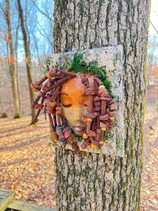 Discover the stunning aesthetic of EL Lay, a handmade raku fire mask adorned with 50 beads and crafted using 24 and 16 gauge wire. This one-of-a-kind piece weighs roughly 3 pounds and is mounted on an 8" x 10" canvas. The earthy two tone face and braided, beaded hair make it a unique addition to your indoor or outdoor decor.