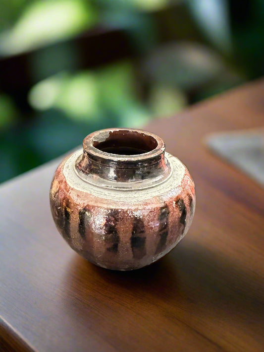 Expertly crafted using the Raku firing technique, this Marv and copper metallic vase boasts a striped design and a 4-inch height and 4 1/2-inch width. With a weight of 15 ounces and a versatile 2 1/2-inch opening, it is suitable for displaying various types of flowers. Its finish is truly one-of-a-kind, making it a stunning addition to any space.