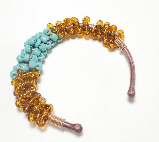 This adjustable copper bracelet features a tasteful mix of amber and baby blue beads. It is sure to provide an elegant touch to any outfit.