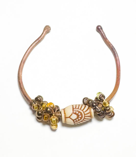 This Copper Beaded Bracelet offers a captivating blend of traditional design and modern styling, showcasing an iconic centerpiece bead with mixed amber beads flanking it. An eye-catching accessory.