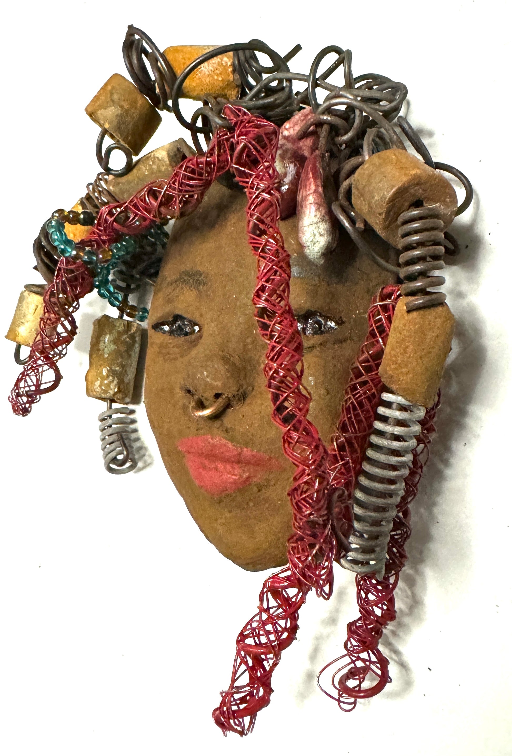 At 5" x 6" in size, Ola makes a stunning addition to walls, trees, and shadow boxes. His signature red braided hair is ornamented with handcrafted Raku beads, while his skin has a warm honey brown hue. Each piece is equipped with over 20 feet of top-notch 16 & 24-gauge wire in the hair. This fashionable sculpture will bring a modern flair to any room - simply place it in a shadow box and enjoy!  