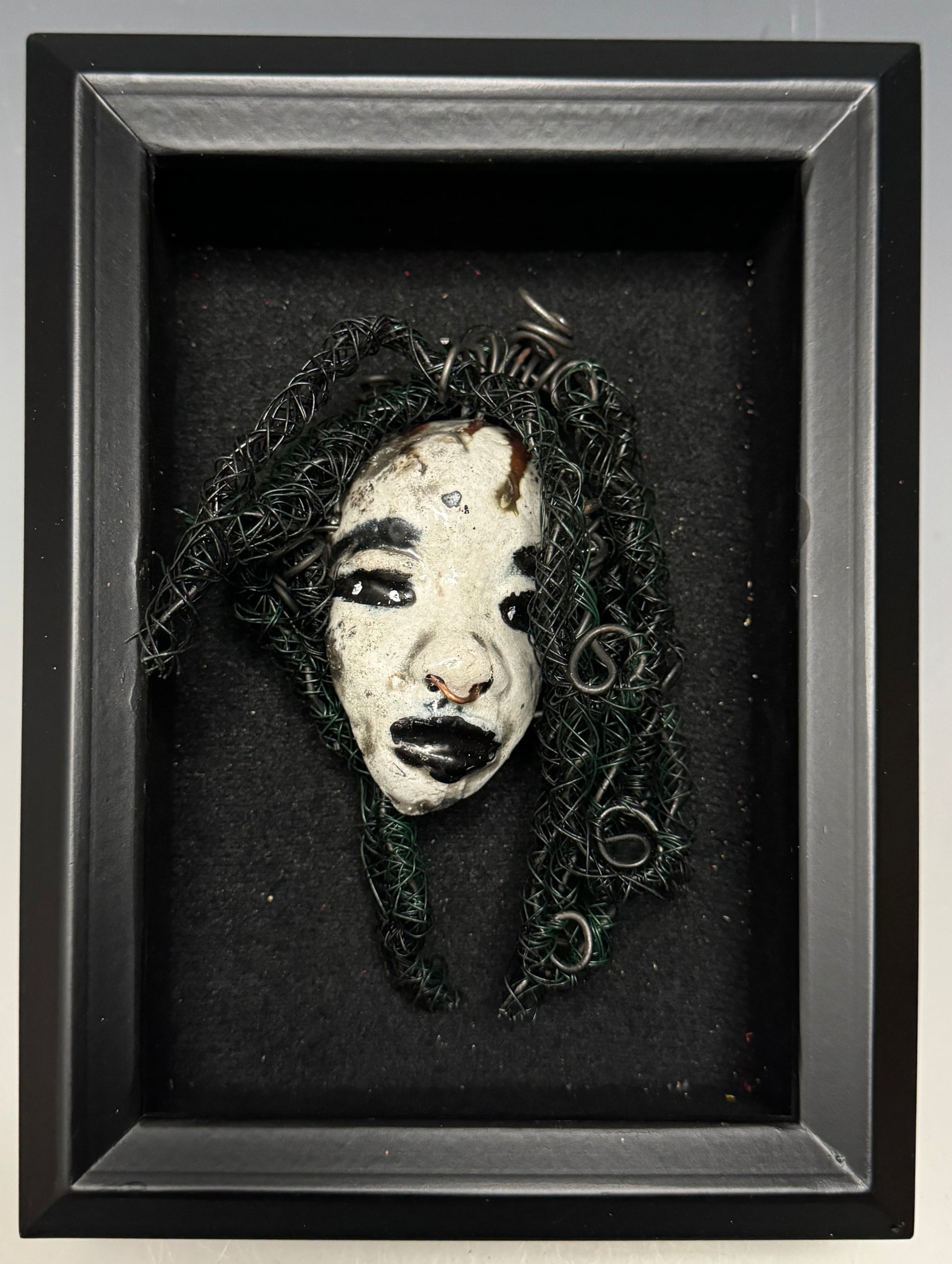 Bongani is a 4x 6” raku-fired mask featuring a pristine off-white color palette. Her intricately detailed hair is composed of nearly 15 feet of 24 gauge wire, delicately adorned. Set in a backdrop of nature, her portrait makes a wonderful addition to any outdoor art collector, or for decorating the home.