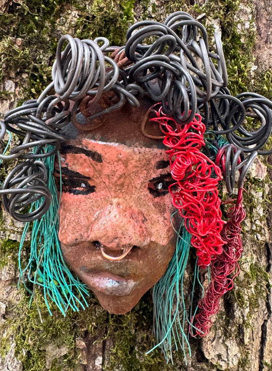 Dakari is an eye-catching two tone tribal raku mask, measuring 4 x 7" and weighing 6 oz. This mask is finished with a stunning blue  and red hair. Dakari also features a copper nose ring. Shadowbox is not included.