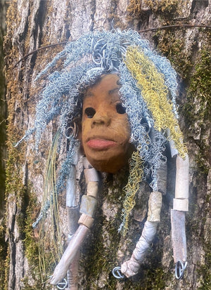 Gina has a two tone honey and beige complexion. She is approximately 6" x 9" and weighs 14 ozs. Gina has an aged earthy hairstyle of handmade textured dreadlocks along with twist of coiled 24 and 16 gauge wire