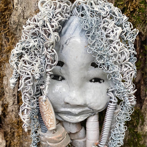 Wei  has an off white complexion with off white lips. She is 6”x 8” and weighs  10 ozs. Wei has more than 10 handmade raku fired beads. Wei has over 70 feet of coiled 24 and 16 gauge wire hair.