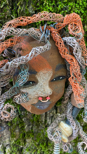 Candela is a  5" x 7" whimsical mask with a cocoa copper complexion. Her handmade textured dreadlocks and coiled 16 gauge wire provide a unique look that's not found in typical masks. Candela is the perfect conversationalist for your wild inquiries, so don't hesitate - give her a shout! 