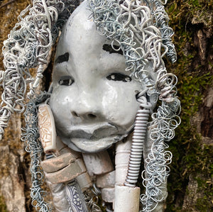 Wei  has an off white complexion with off white lips. She is 6”x 8” and weighs  10 ozs. Wei has more than 10 handmade raku fired beads. Wei has over 70 feet of coiled 24 and 16 gauge wire hair.