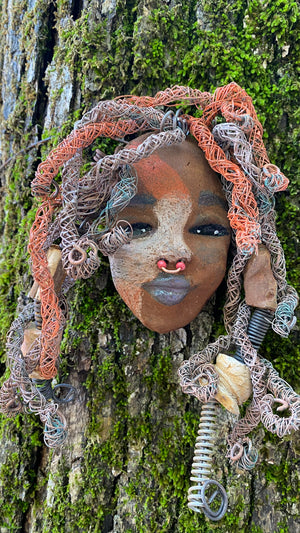 Candela is a  5" x 7" whimsical mask with a cocoa copper complexion. Her handmade textured dreadlocks and coiled 16 gauge wire provide a unique look that's not found in typical masks. Candela is the perfect conversationalist for your wild inquiries, so don't hesitate - give her a shout! 