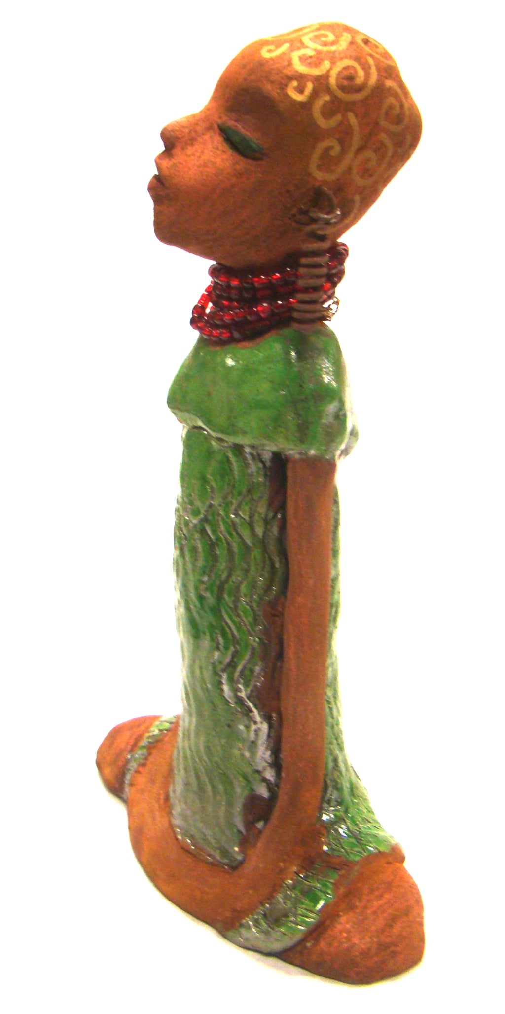      Amaya stands 10" x 6" x 2.5" and weighs 1.03 lbs.     She has a lovely honey brown complexion.     Her hair is drawn with spiral gold ink.     Amaya long loving arms rest beside her alligator green dress.     She wears a strand of ruby red beads with spiral wire ear rings.     Amaya is a sophisticated lady that will grace your home.     Free Shipping!