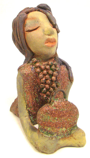 Lacey stands 6" x 3" x 7.5" and weighs 1.08 lbs. She has a lovely beige olive green complexions with ruby red lips. Her hair is made of coiled clay. Lacey is holding her handbag which matches her copper glittered dress. Give Lacey a special place in your home.