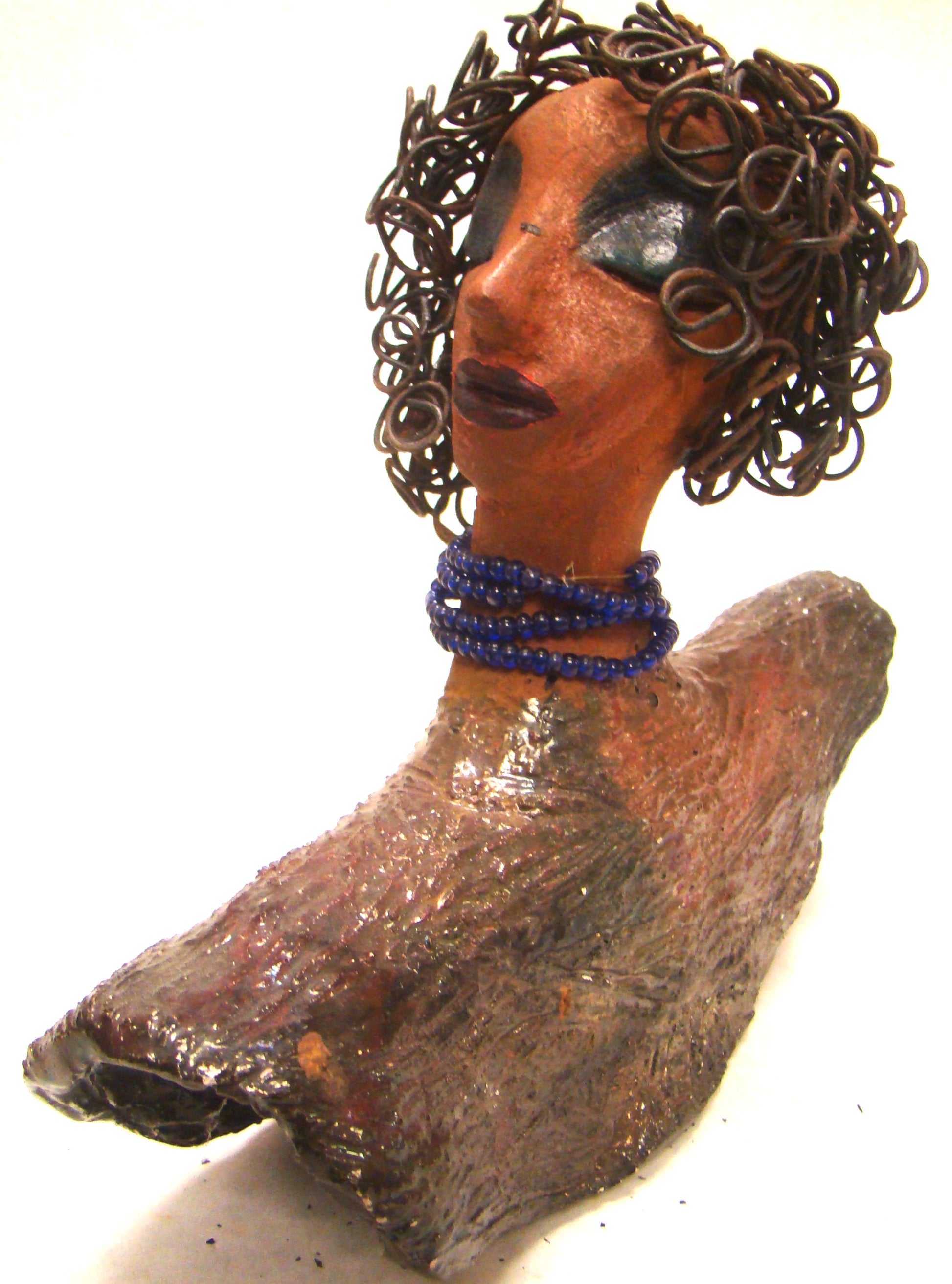 Helen stands 8" x  8" x 3" and weighs 2.06 lbs. She has a lovely honey brown complexion. Helen has a metallic copper glaze on her textured robe. Her blue eye shadow matches the blue strand of beads around her neck. Helen has over 20 feet of curly wire hair. Helen is somewhat angelic! Give Helen a prominent place in your home!
