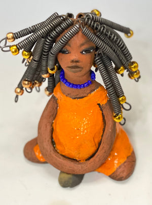 Meet Destiny!  Destiny stands 6.5" x 5" x 4" and weighs 1.05 lbs. She wears a lovely glossy sunset orange dress adorn by a blue beaded necklace. Destiny has over25 feet of 16 gauge coiled wire hair with gold beads.. Destiny appears to sit in a yoga pose. Her long arms rest at her side. Destiny is a great starter piece from the Herdew Collection!