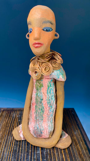 " I am really pleased with Jada's copper coiled necklace. It complements her well!" Jada stands 9" x 4.5" x 2.5" and weighs 1 lb. She has a lovely two tone honey brown complexion. Jada is one of a few without Hair! Jada's dress is a metallic glaze with copper red stripes. She has her long loving arms resting at her side. Find a place in your space for Jada!
