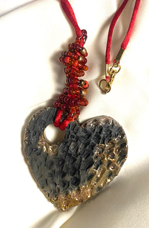 Have A Heart ! Each heart pendant is handmade with love! It is 3"x 3" and weighs approx. 3ozs. This pendant has a copper gold metallic raku glazes that renders a unique translucent  patina. The heart has a textured pattern . It holds a spiral of red mini beads on a spiral copper wire. This pendant has a nice 12" red suede cord!