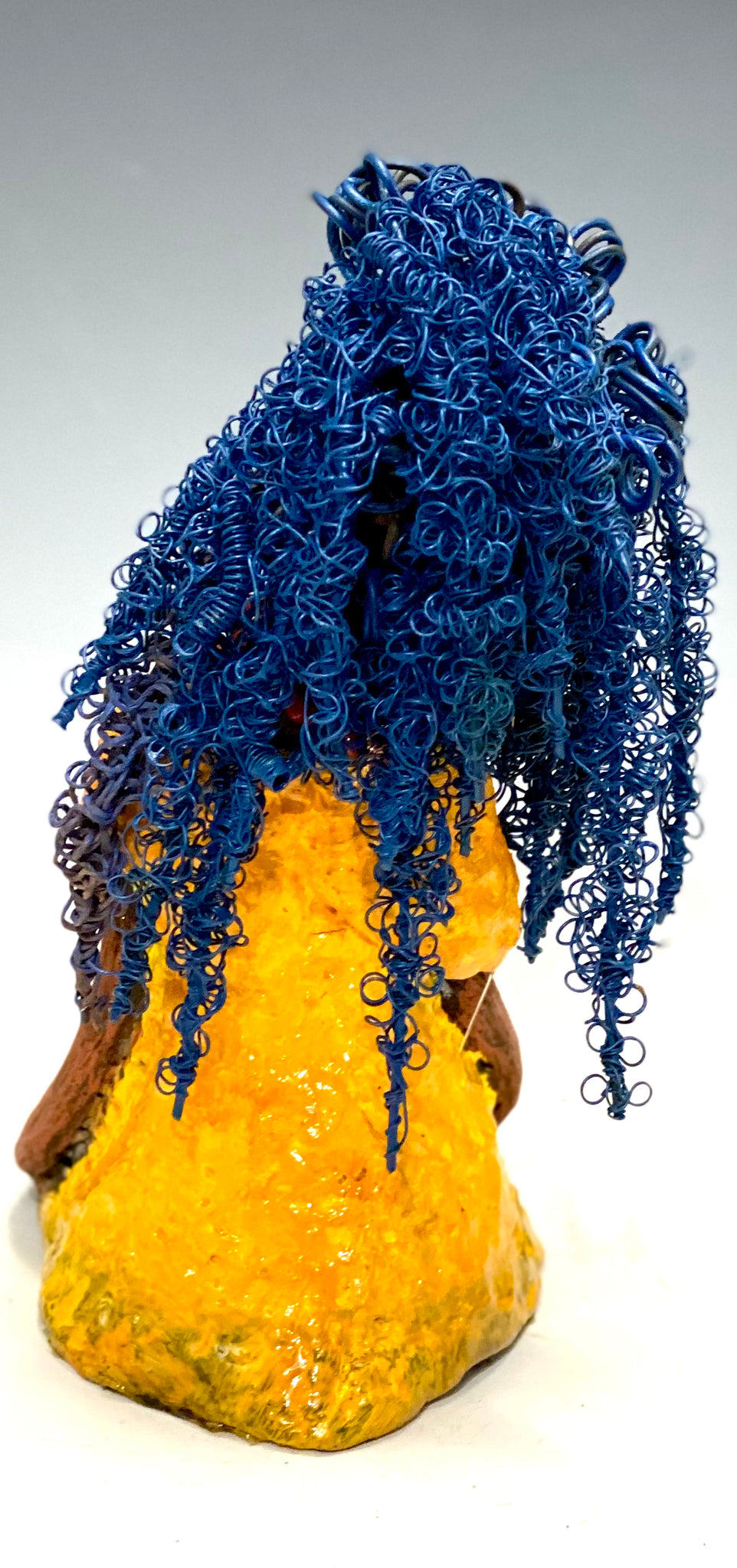 Makeba stands 8" x 5" x 5" and weighs 1.4 lbs. She has a lovely honey brown complexion with cocoa red lips. She has long twisted  blue wire locs hairstyle waist down!  Makeba has a sunset yellow red glazed dress. She has over 75 feet of 16 and 24 gauge blue wire for hair. It took over 5 hours just to do her hair! With  eyes wide opened and a subdue look, Makeba has hope of finding a new home.