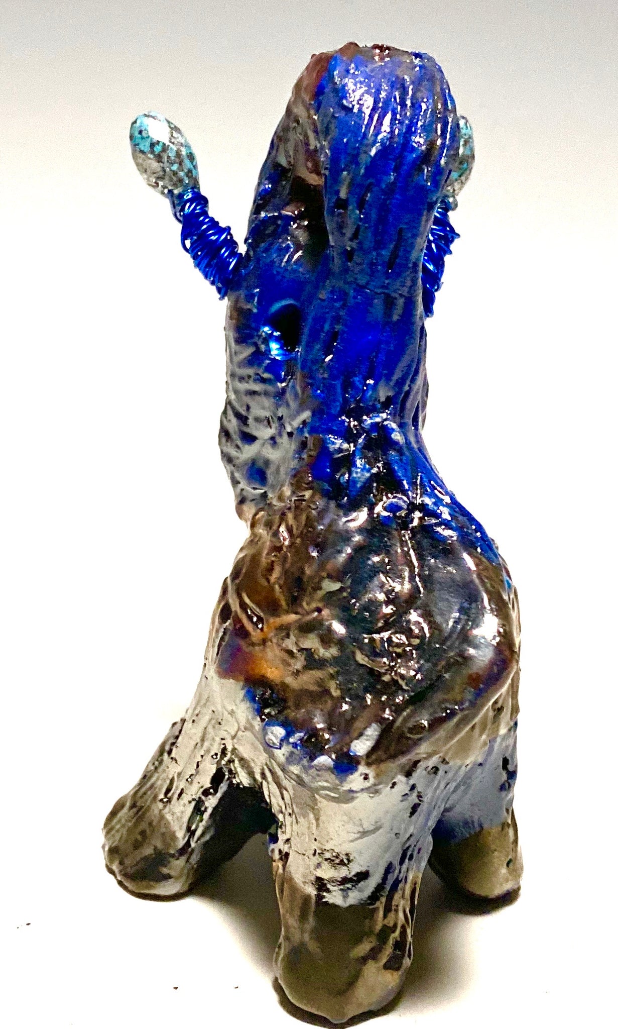 Raku Elephant Have you HERD!!!!!!  Just one of these lovely Raku Fired Elephant will make an excellent gift for your  friend, sorority or for your home’ special place centerpiece.  5" x 4" x 4" 9 ozs. Blue wire beaded blue tusk Beautiful metallic raku colors For decorative purposely only.