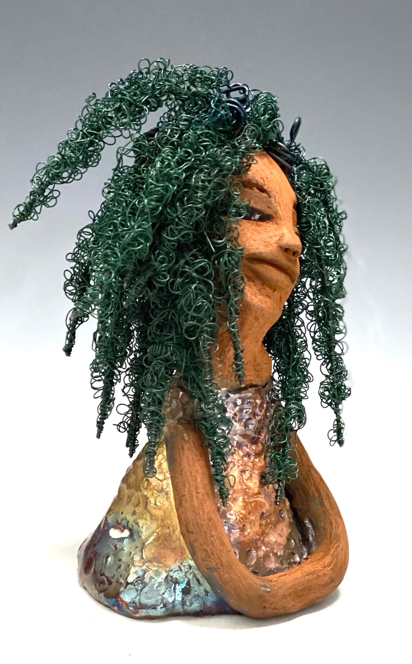 Nia Nia stands 8" x 5" x 5.5" and weighs 1.04 lbs. She has a lovely honey brown complexion with soft brown lips. She has long twisted wire locs hairstyle waist down!  Nia has a glossy metallic copper glazed dress. She has over 75 feet of 16 and 24 gauge emerald green wire for hair. It really took over 6 hours just to twist and do her hair! With  eyes wide opened, Alexis has hope of finding a new home.   