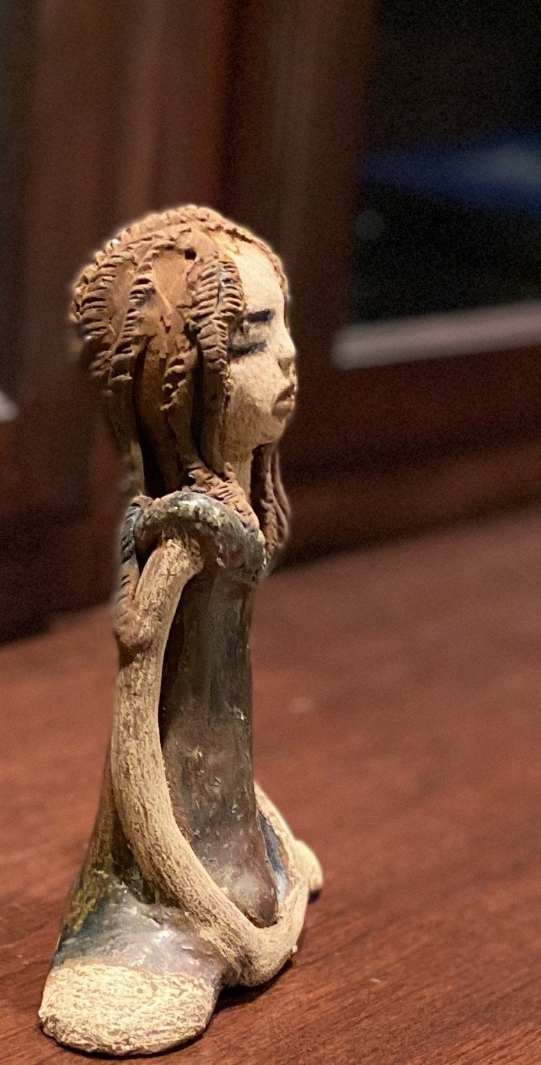 Amani stands 8" x 5" x 2.5" and weighs 1.03 lbs. She has a lovely beige brown complexion with long etched braided clay hair.   Amani long loving arms rest beside her copper green dress. Amani is a sophisticated lady that will grace your home.