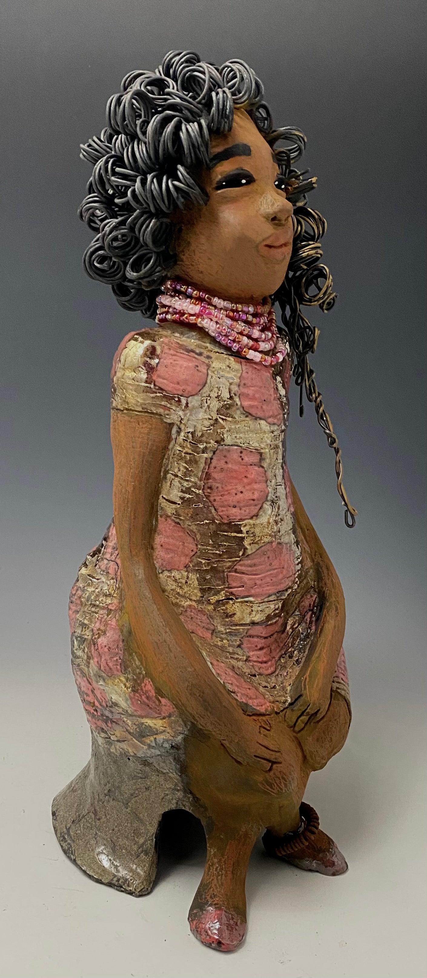 Meet Jasmine! Jasmine stands 18' x 6" x 5" and weighs 5.03 lbs. Jasmine has a lovely honey brown complexion. She has a shimmering copper red and gold dress with a red and off white beaded necklace. Jasmine is a tall girl with long loving arms. It took several hours to style Jasmine's 16 gauge two tone  wire hair! She looks as if she's dreaming or in disbelief.  I am proud of how Jasmine turned out! She appears to be a happy and sophisticated  lady!  