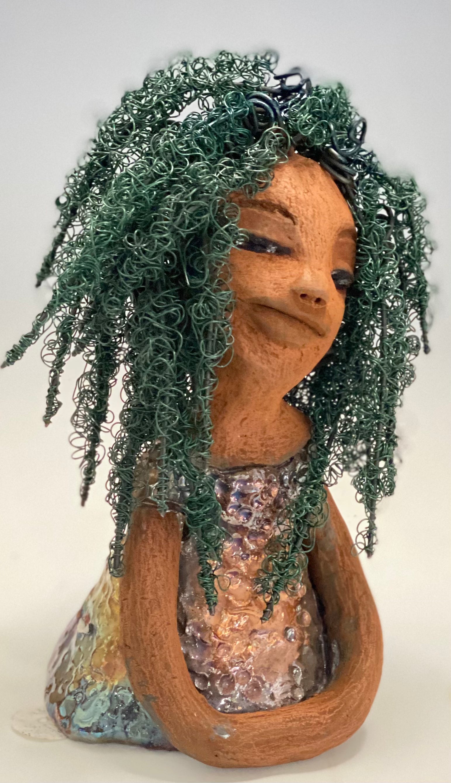 Nia Nia stands 8" x 5" x 5.5" and weighs 1.04 lbs. She has a lovely honey brown complexion with soft brown lips. She has long twisted wire locs hairstyle waist down!  Nia has a glossy metallic copper glazed dress. She has over 75 feet of 16 and 24 gauge emerald green wire for hair. It really took over 6 hours just to twist and do her hair! With  eyes wide opened, Alexis has hope of finding a new home.   