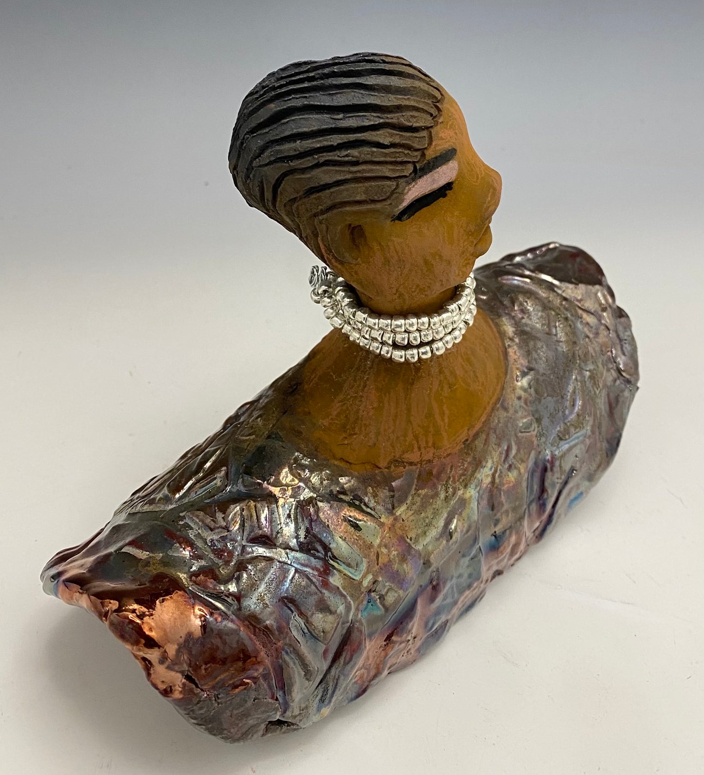 Belinda looks up with joy and anticipation! Belinda stands 6" x 8" x 4" and weighs 1.40 lbs. She has a beautiful textured copper robe trim. Belinda has braided clay hair. She has a honey brown complexion and soft light brown lips. Belinda will make for great conversation in your home.