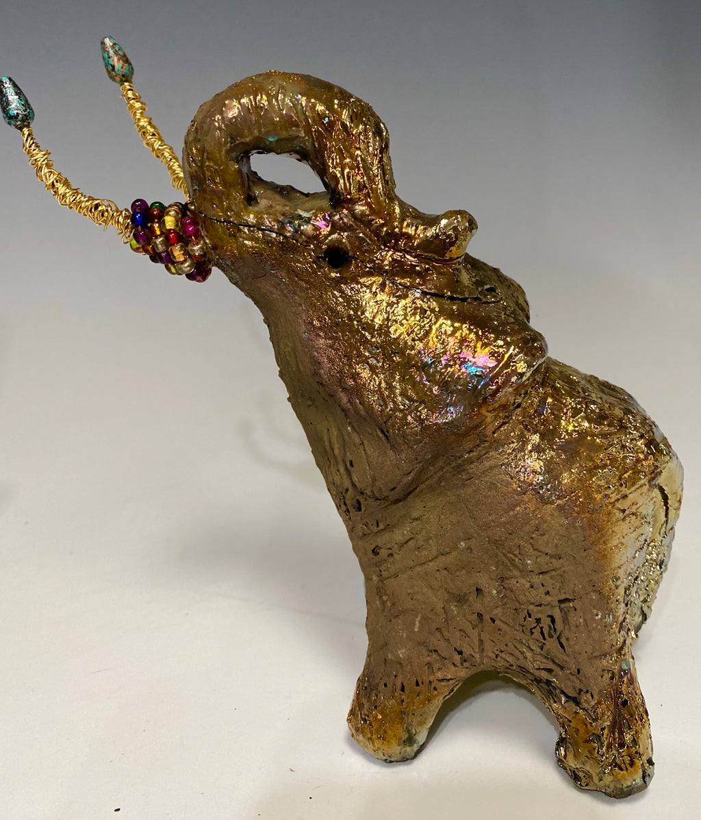 Have you HERD!!!!!!     Elephants are one of my favorite animals to create. They are so majestic"  Just one of these lovely Raku Fired Elephant will make an excellent gift for your  BFF,  or just for you .    This raku fired elephant stands 6" x 4" x 6" and weighs 1.3 lb. She has beaded tusks and a textured glossy gold and copper metallic body. This one is nice to add your Herdew Collection!
