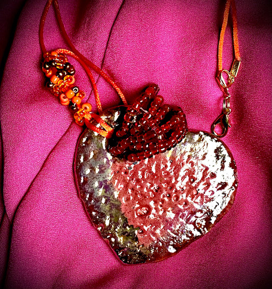 Have A Heart ! Each heart pendant is handmade with love! It is 3"x 3" and weighs approx. 3ozs. This pendant has a red violet and gold metallic raku glazes that renders a unique translucent  patina. The heart has a textured pattern . Both sides are  are different and equally beautiful! It holds a spiral of red violet mini beads on a spiral copper wire. This pendant has a nice 12" red suede cord!