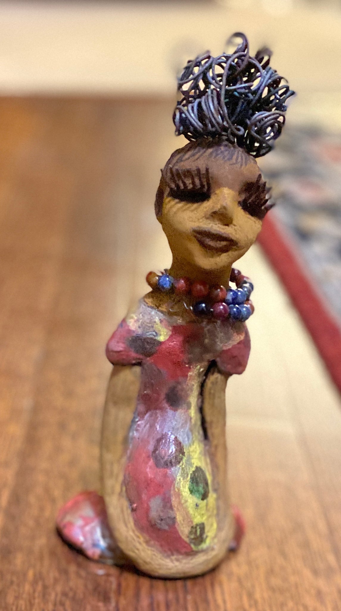  You know someone like Tiffanie. One who reaps elegance and sophistication!  Tiffanie stands 9”x 4" x 4" and weighs 1.03 lbs.  She has a two tone light beige complexion with 2 feet of 16 gauge spiral coiled wire hair.  Tiffanie metallic copper red and yellow  dress is accented by a multicolored beaded necklace. Tiffanie’s long lashes and  black eye shadow gives her a distinguished mystical look. 