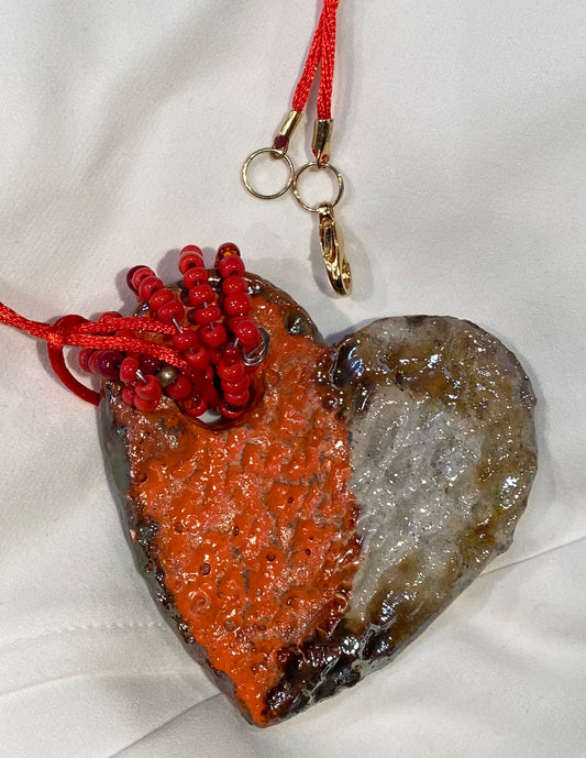 Have A Heart ! Each heart pendant is handmade with love! It is 3"x 3"and weighs approx. 3ozs. This pendant has a red violet and gold metallic raku glazes that renders a unique translucent  patina. The heart has a textured pattern . Both sides are  are different and equally beautiful! It holds a spiral of red and gold mini beads on a spiral copper wire. This pendant has a nice 12" red rattail cord!