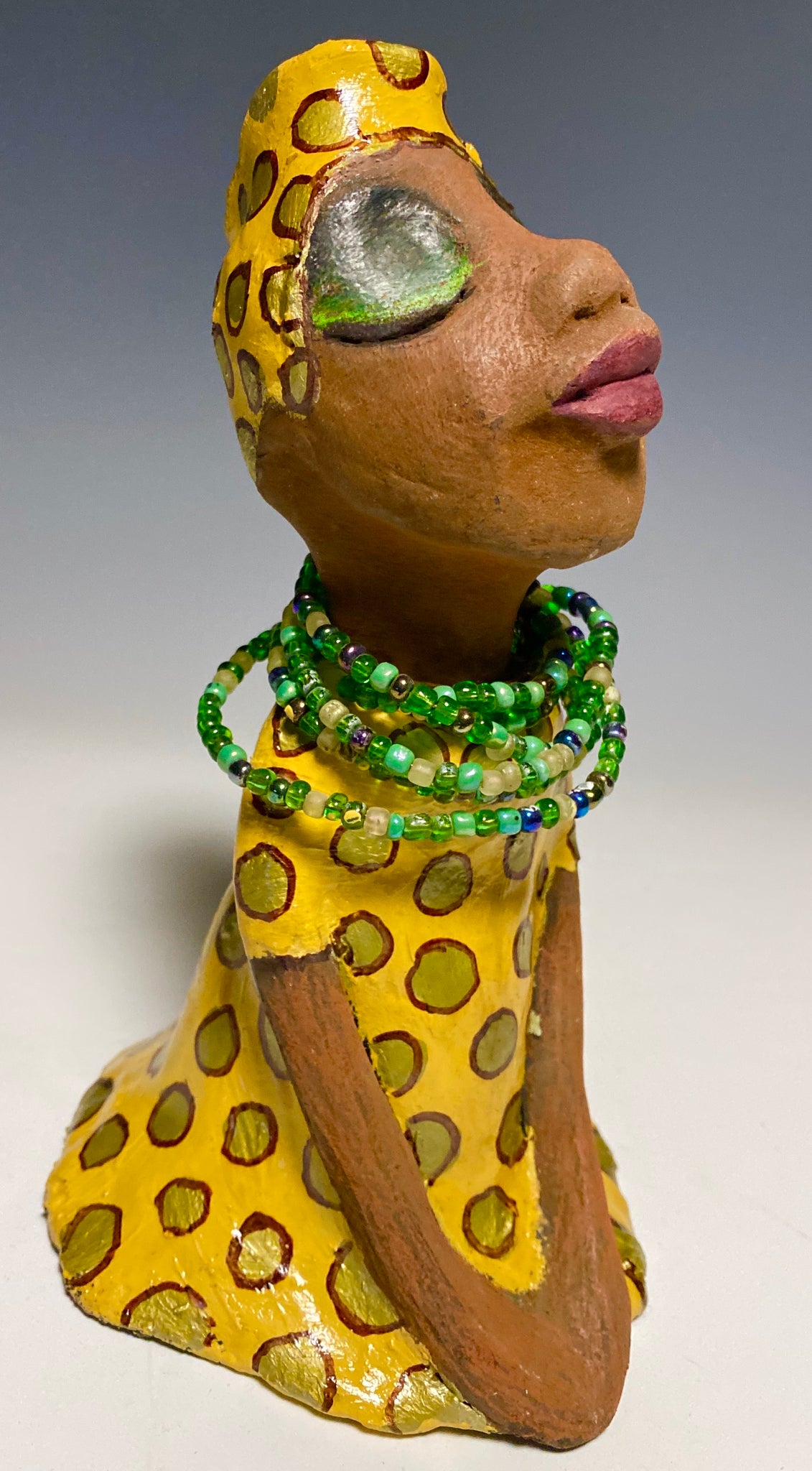 Meet Sharon! Sharon stands" 8 x 5" x 5" and weighs 1.5 lbs She wears a cute spotted autumn yellow dress with matching hat and emerald green beads. Her long loving arms rest at her side. Check out Sharon's little sister named Shelia! With the current situation we All are going through, Shelia will place a smile on your face during this challenging time. 