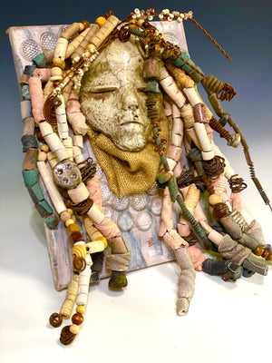 Alaskaya is mounted on a 9"x 12" painted canvas. I spent about 4 hours or more just fixing Alaskaya's hair and attaching her beads! She has over 50 feet of 16 gauge wire and copper strands for hair and over 50 raku beads. Alaskaya weighs 4.03 lbs. Alaskaya has a white crackle face with an angelic demeanor. Alaskaya is ready to be hung!