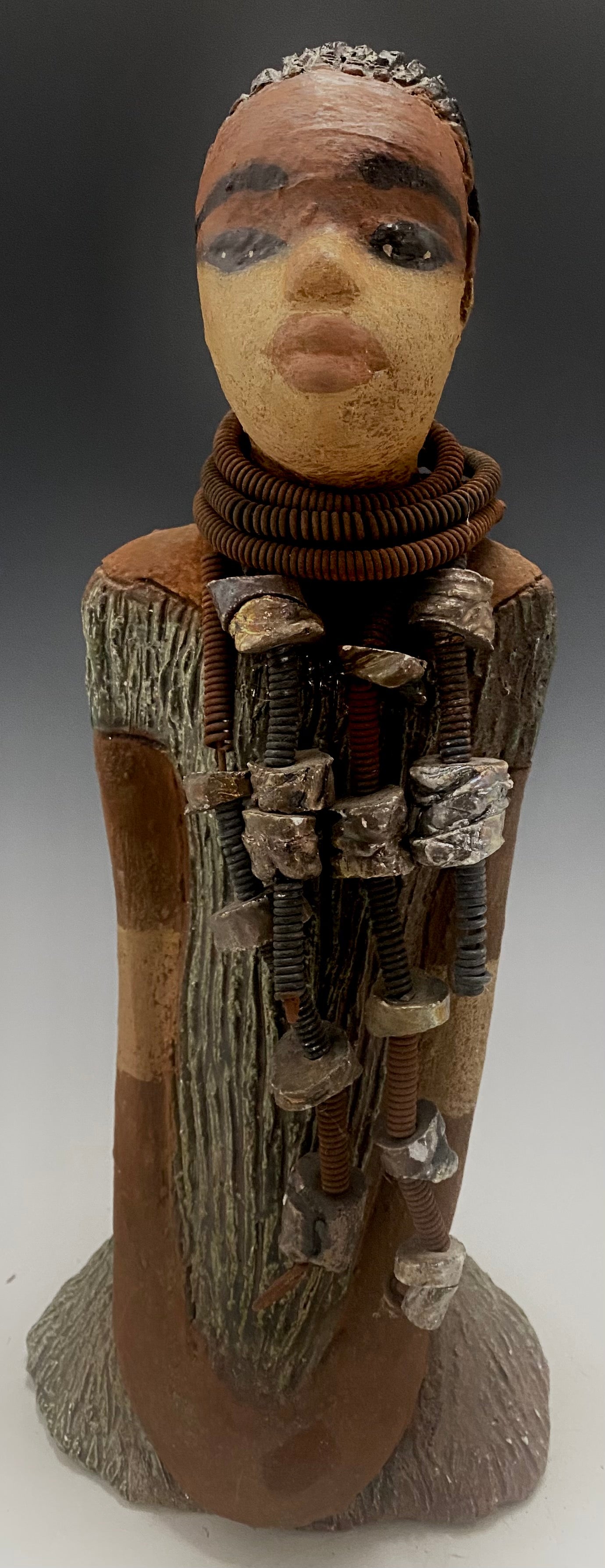 Meet Jana J! Jana J stands 13" x 6" x 5" and weighs 3.09 lbs Jana has a lovely two tone honey brown complexion. She wears a long strand of raku beads around her neck. Give Jana J in a special place in your home!