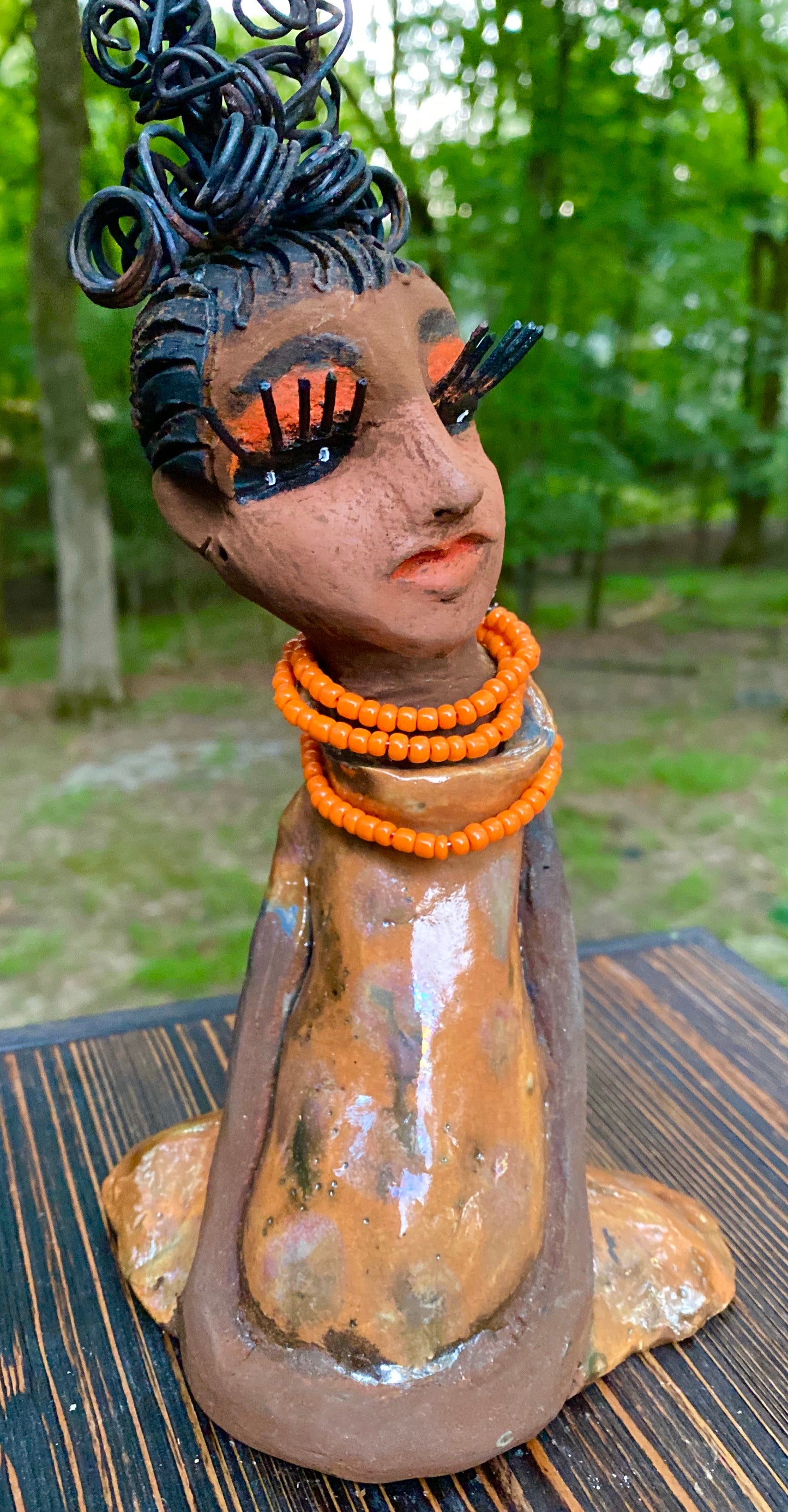 Meet Abimbola ! Abimbola stands 7' x 4"x 2" and weighs 1.3 lb. She has bright eyes and a nice honey brown complexion Abimbola  has over 5 feet of 16 gauge wire hair wrapped in a bun. Her long trademark arms rest at her side. Abimbola dress is a loving glossy orange mix with copper flashes. Abimbola is waiting for you to invite her into your home! 