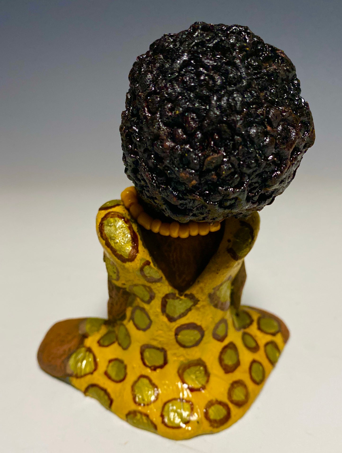 Meet Shelia! Shelia stands" 5 x 4" x 3" and weighs 11 ozs. She wears a cute spotted autumn yellow dress with matching beads. She has a lovely honey brown complexion with an awesome black afro.. Her long loving arms rest at her side. With the current situation we All are going through, Shelia will place a smile on your face during this challenging time. 