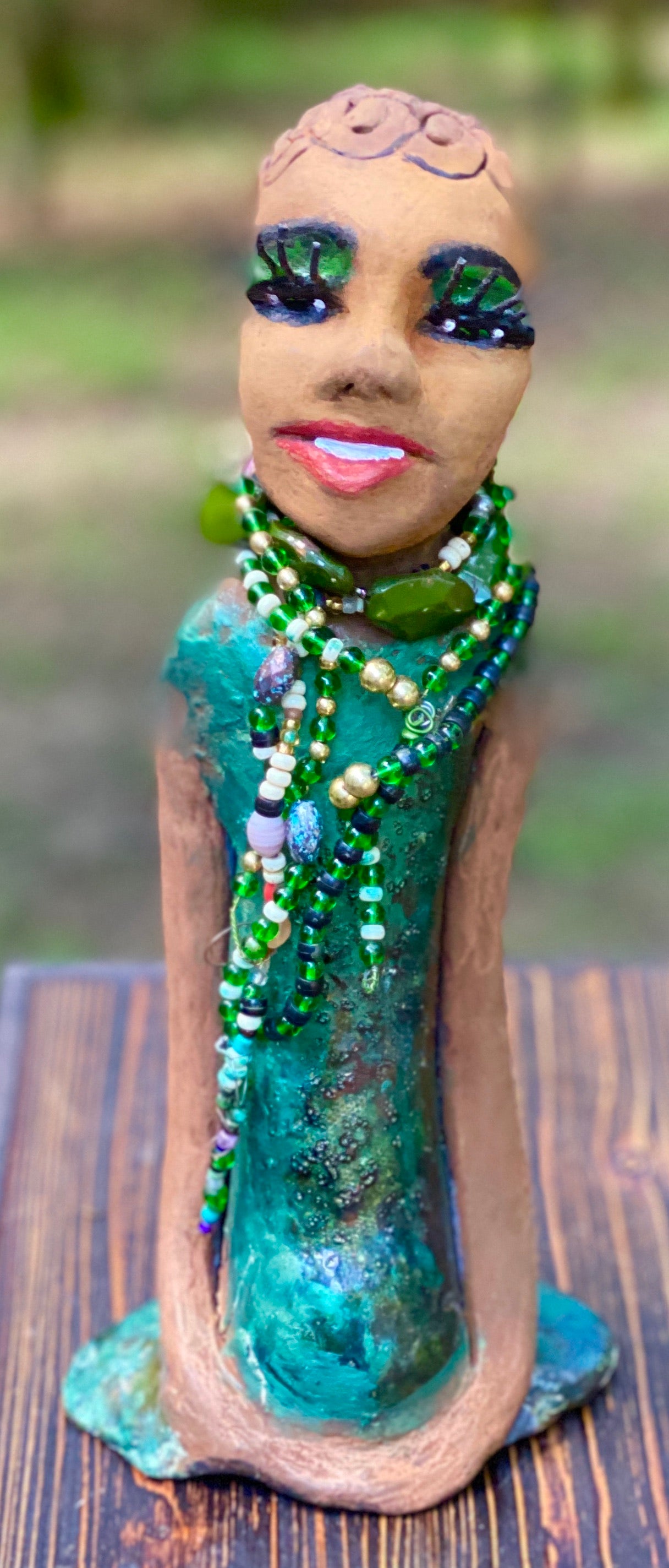 Meet Makeda What a joy to be around Makeda! She is one of many who has a polite gentle spirit! Makeda 12" x 6" x 4" and weighs 1.1 lbs. Makeda has a lovely honey brown complexion. Her  hair is made of textured clay. She has very loooong eyelashes! She has a  copper green metallic dress. Makeda Is a a young  lady full of pride and joy. If you like sophisticated  sculptures, Makeda will bring joy and peace to your home.