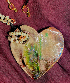  Have A Heart! Each heart pendant is handmade with love! It is 3"x 3" and weighs approx. 3ozs. This pendant has a copper gold metallic raku glazes that renders a unique translucent  patina. The heart has a textured pattern . It holds a spiral of white mini beads on a spiral copper wire. This pendant has a nice 12"black rattail cord!
