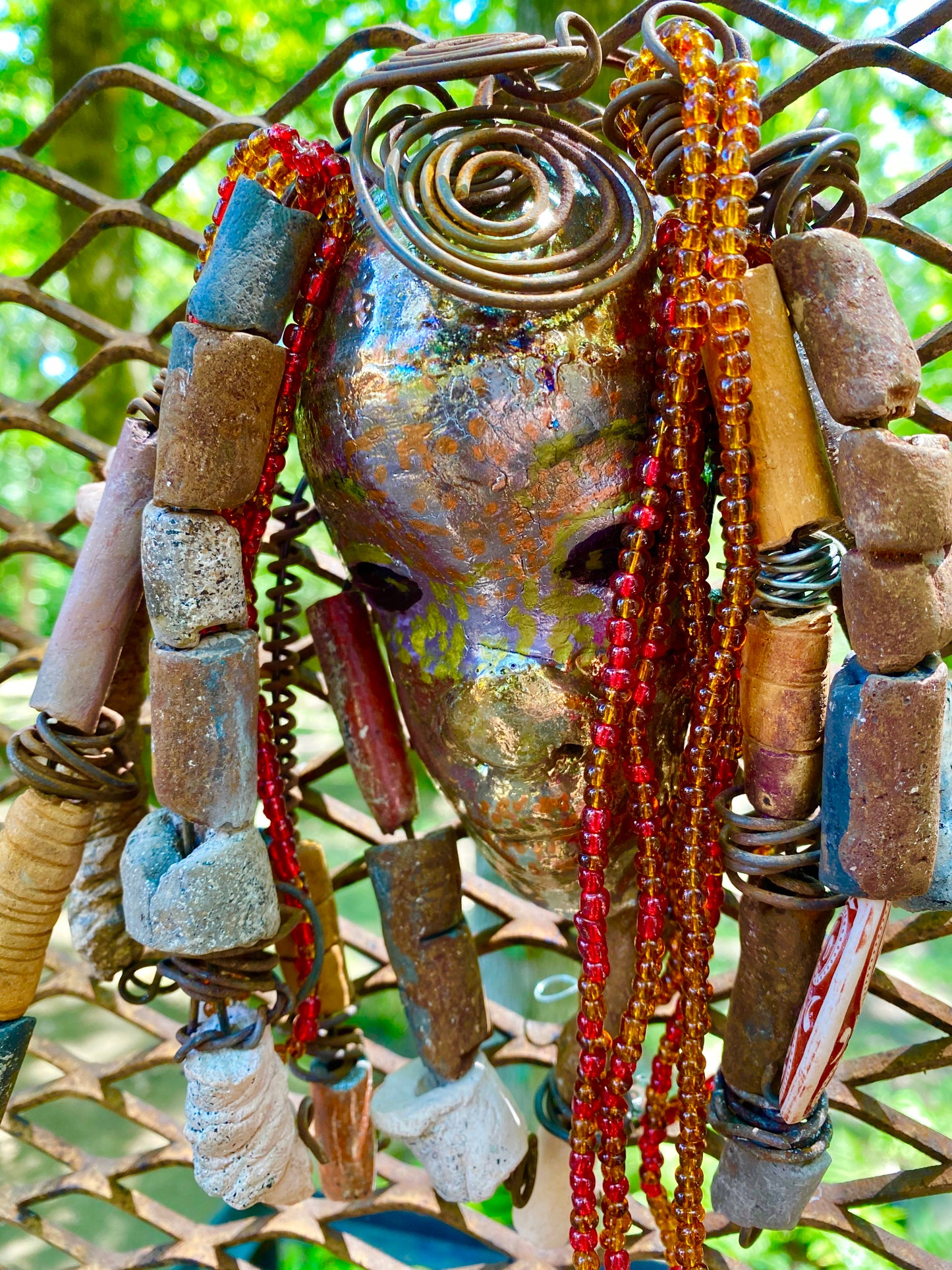 I started making mask soon after seeing authentic African artwork at the Smithsonian Museum of African Art. I was in total awe. Makeda means she who discovers the soul of others and things was inspired by my visit there.  Makeda has a two tone  metallic copper gold complexion. She is 7" x 5" and weighs 1lbs. Makeda has  over 20 handmade raku fired beads. She has over 100 mini amber and red beads twisted as hair. Makeda has over 10 feet of  copper coiled 16 gauge wire hair.
