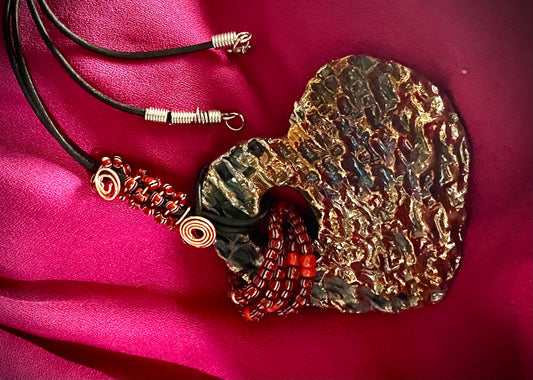 Have A Heart ! Each heart pendant is handmade with love! It is 3"x 3" and weighs approx. 3ozs. This pendant has a gold metallic raku glazes that renders a unique translucent  patina. The heart has a textured  pattern. It holds a spiral of ruby mini beads on a spiral copper wire. This pendant has a nice 12" black suede cord!